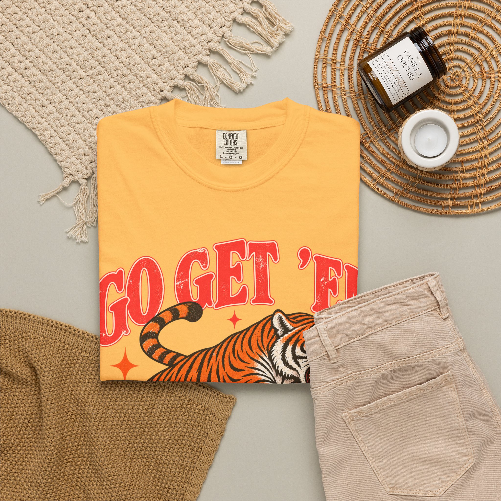 Yellow Go Get ’Em Tiger T-shirt, folded with the front design visible beside beige trousers.