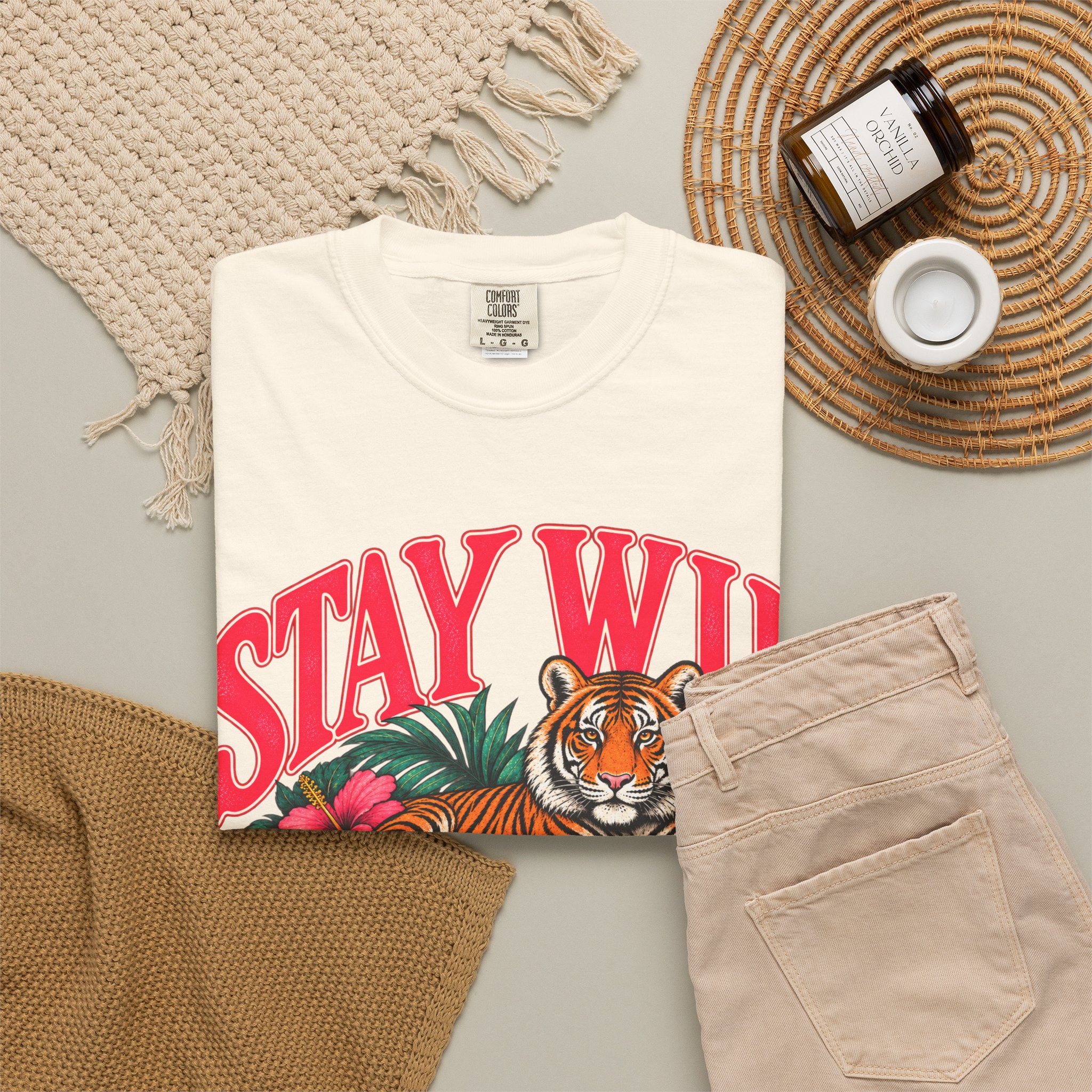 Cream Stay Wild T-shirt, folded with the front design visible beside beige trousers.